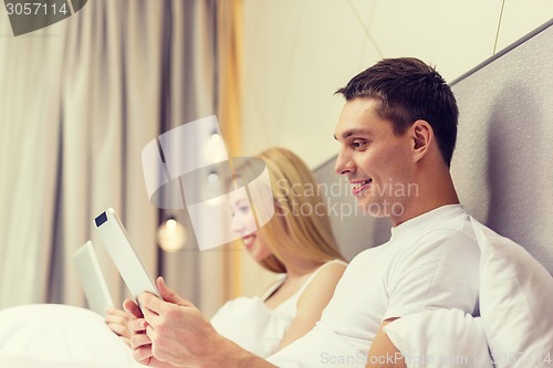 Image of smiling couple in bed with tablet pc computers