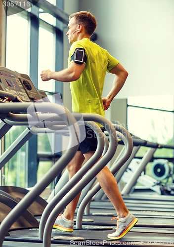 Image of man with smartphone exercising on treadmill in gym