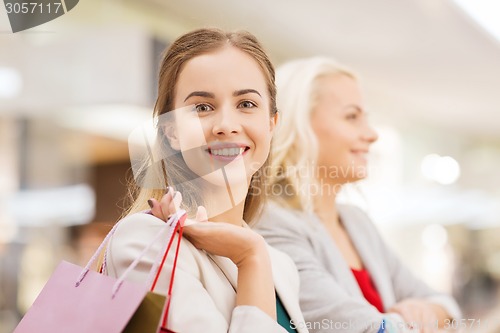 Image of happy young women with shopping bags in mall