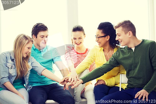 Image of smiling students with hands on top of each other