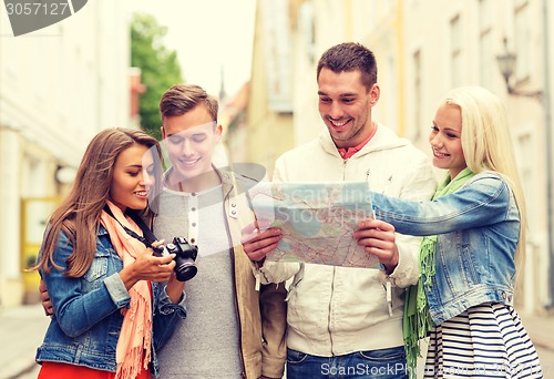 Image of group of smiling friends with map and photocamera