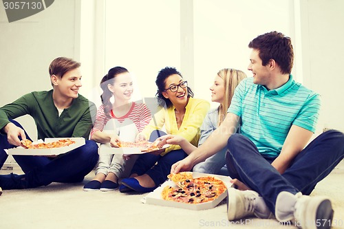 Image of five smiling teenagers eating pizza at home