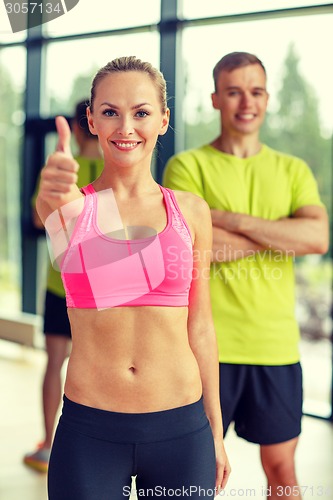 Image of smiling man and woman showing thumbs up in gym