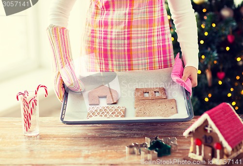 Image of closeup of woman with gingerbread house on pan