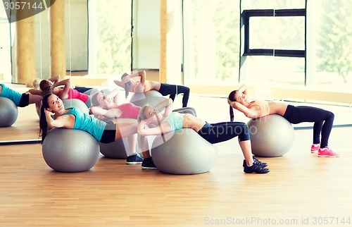 Image of group of smiling women with exercise balls in gym