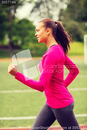Image of smiling woman running on track outdoors