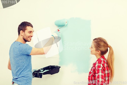 Image of smiling couple painting wall at home