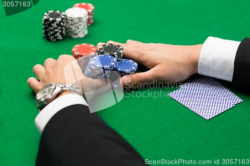 Image of poker player with cards and chips at casino