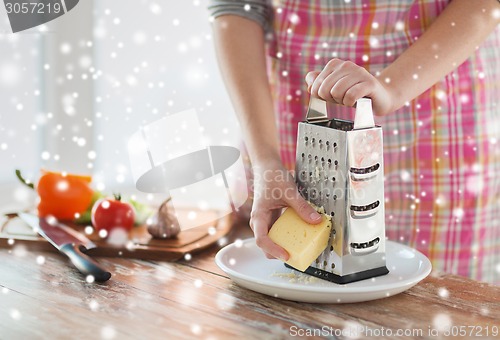 Image of close up of woman hands with grater grating cheese