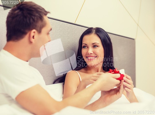 Image of man giving woman little red gift box