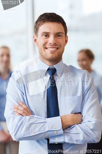 Image of smiling businessman with colleagues in office