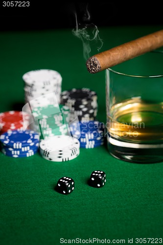 Image of close up of chips, dice, whisky and cigar on table