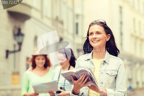 Image of smiling teenage girls with city guides and camera