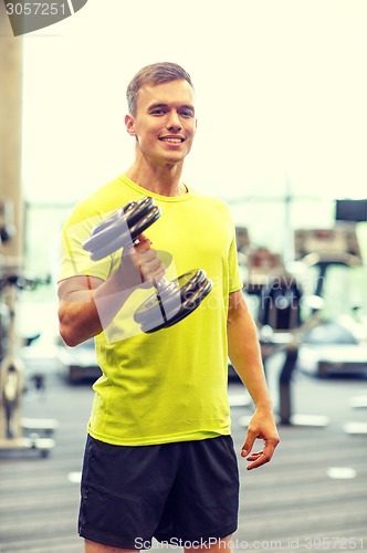 Image of smiling man with dumbbell in gym