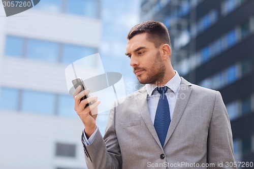 Image of serious businessman with smartphone outdoors