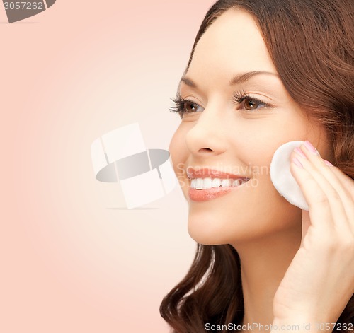 Image of smiling woman cleaning face skin with cotton pad