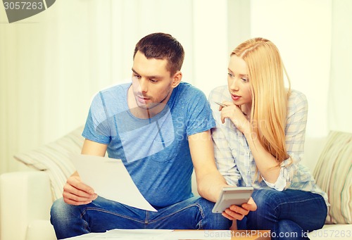 Image of busy couple with papers and calculator at home