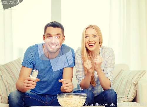 Image of smiling couple with popcorn cheering sports team