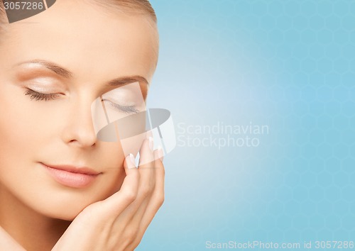 Image of beautiful young woman touching her face
