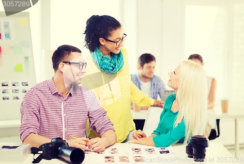 Image of smiling team with printed photos working in office