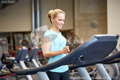 Image of smiling woman exercising on treadmill in gym