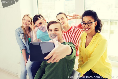 Image of smiling students making picture with tablet pc