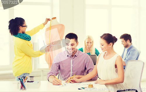 Image of smiling fashion designers working in office