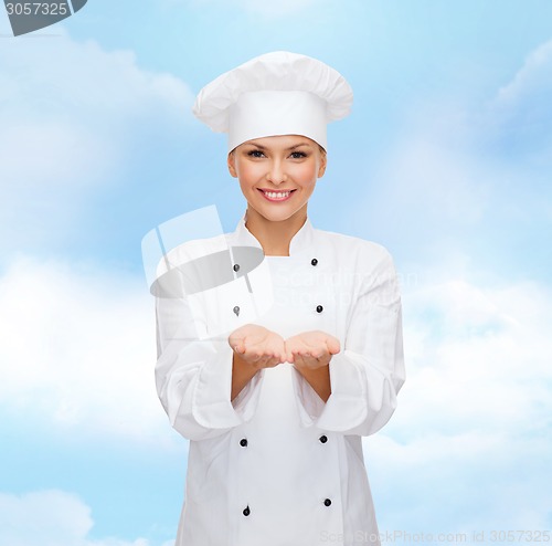 Image of smiling female chef holding something on hands