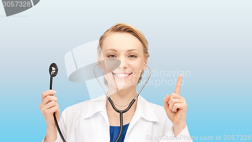 Image of smiling young female doctor over blue background