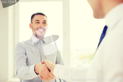 Image of two smiling businessmen shaking hands in office