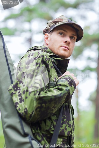 Image of young soldier or hunter with gun in forest