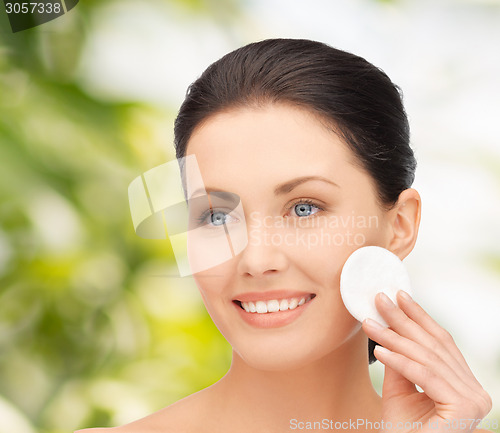 Image of smiling woman cleaning face skin with cotton pad