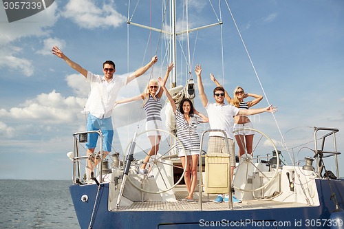 Image of smiling friends sitting on yacht deck and greeting