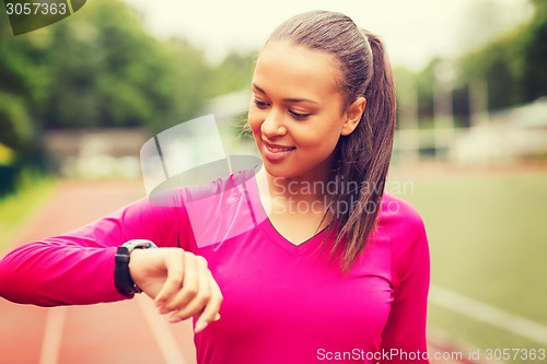 Image of smiling woman running on track outdoors