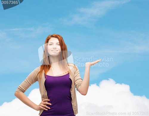 Image of smiling teenage girl holding something on her palm