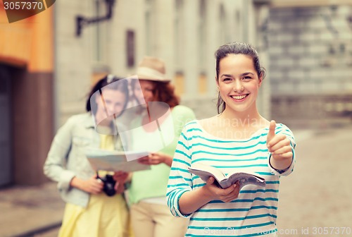 Image of smiling teenage girls with city guide and camera