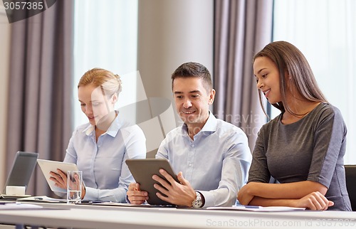 Image of smiling business people with tablet pc in office