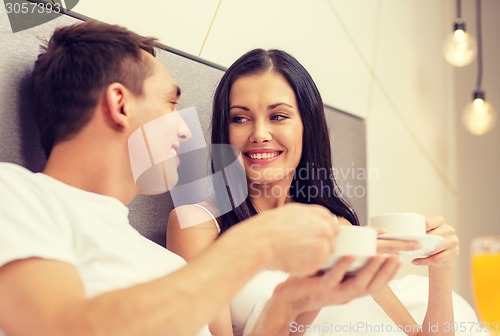 Image of smiling couple having breakfast in bed in hotel