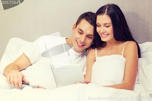 Image of smiling couple in bed with tablet pc computers