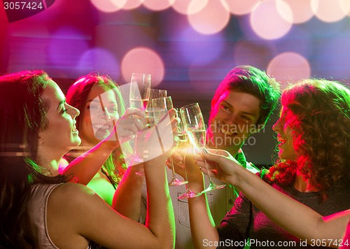 Image of smiling friends with glasses of champagne in club