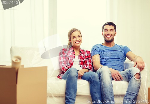 Image of smiling couple relaxing on sofa in new home