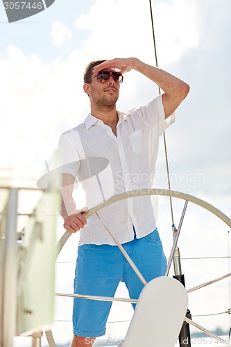 Image of young man in sunglasses steering wheel on yacht