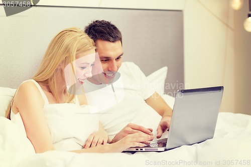 Image of smiling couple in bed with laptop computer