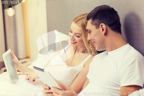 Image of smiling couple in bed with tablet pc computers