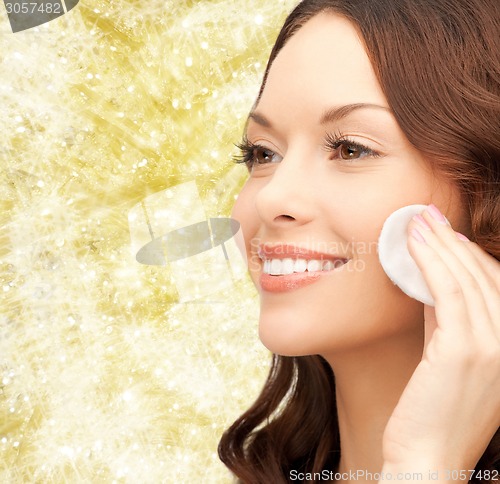 Image of smiling woman cleaning face skin with cotton pad