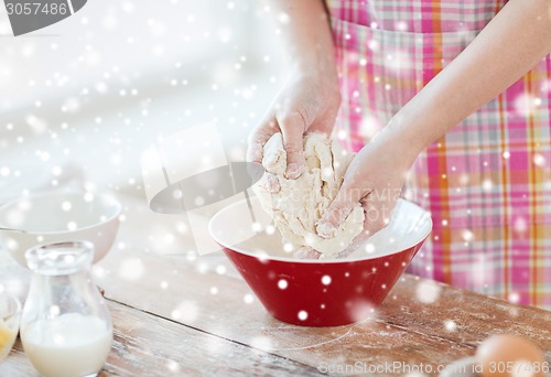 Image of close up of female hands kneading dough at home