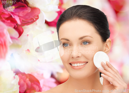 Image of smiling woman cleaning face skin with cotton pad