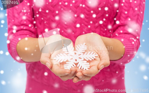 Image of close up of woman in sweater holding snowflake