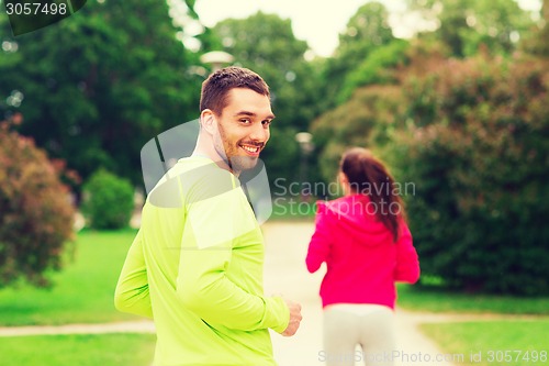 Image of smiling couple running outdoors