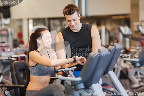 Image of happy woman with trainer on exercise bike in gym